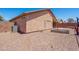 The back exterior shows a well maintained stucco house and a gravel yard at 9175 E Rainier Dr, Gold Canyon, AZ 85118
