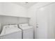 Bright laundry room features a washer, dryer, overhead shelving, and white door at 9175 E Rainier Dr, Gold Canyon, AZ 85118