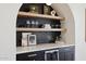 Chic bar area with floating shelves, marble countertop, a wine fridge and stylish decor at 9322 E Hidden Green Dr, Scottsdale, AZ 85262
