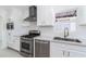 Renovated kitchen with stainless steel appliances, white cabinetry, and a sleek range hood at 1011 W Weldon Ave, Phoenix, AZ 85013