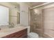 Bathroom with a glass-enclosed shower, brown tile, and sink with wooden cabinet at 13408 N 25Th Dr, Phoenix, AZ 85029