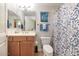 Well-lit bathroom featuring a wood vanity, framed mirror, and a toilet with a patterned shower curtain at 14815 N Fountain Hills Blvd # 101, Fountain Hills, AZ 85268