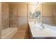 Bathroom featuring double sink vanity, tan tile floors, decorative shower tile and large mirror at 16021 N 30Th St # 122, Phoenix, AZ 85032