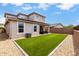 Exterior of a two-story home with a well-manicured backyard lawn, covered patio, and rock landscaping at 16539 W Winston Dr, Goodyear, AZ 85338