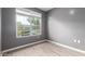 Clean and simple bedroom with wood-look tile floors and a bright window at 16539 W Winston Dr, Goodyear, AZ 85338