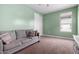 Comfortable bedroom with neutral carpet, a gray sofa, and natural light at 16539 W Winston Dr, Goodyear, AZ 85338