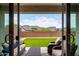A covered patio features comfortable seating and a view of a lush lawn and mountain landscape at 16539 W Winston Dr, Goodyear, AZ 85338