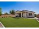 Spacious backyard with a well-maintained lawn, covered patio with seating, and desert landscaping at 17506 W Hadley St, Goodyear, AZ 85338