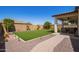 Landscaped backyard featuring a covered patio with outdoor seating, a lush lawn, and accent lighting at 17506 W Hadley St, Goodyear, AZ 85338