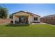 Lush backyard featuring a covered patio with seating, a spacious lawn, and desert-style landscaping at 17506 W Hadley St, Goodyear, AZ 85338