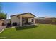 Well-maintained backyard with green lawn, covered patio, and desert landscaping providing a private outdoor space at 17506 W Hadley St, Goodyear, AZ 85338