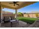 Inviting covered patio with ceiling fan, string lights, and seating area overlooking a spacious green lawn at 17506 W Hadley St, Goodyear, AZ 85338