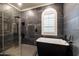 Elegant bathroom featuring a freestanding black tub, glass-enclosed shower, and sleek dark tile at 20639 W Grandview Dr, Buckeye, AZ 85396