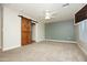 Large carpeted bedroom with ceiling fan, modern barn door, and a wall-mounted TV at 2150 W Alameda Rd # 1109, Phoenix, AZ 85085