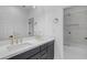 Bright bathroom featuring a double sink vanity with black cabinets and gold fixtures, plus a glass shower with a tiled interior at 22317 N 39Th Run, Phoenix, AZ 85050