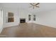 An empty living room featuring large windows, a ceiling fan and a cozy fireplace at 2434 S Colleen Sw --, Mesa, AZ 85210