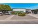 Home exterior featuring landscaped front yard with mature tree, flowering bushes, and carport at 2650 W Union Hills Dr # 164, Phoenix, AZ 85027