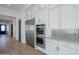 Kitchen showcases stainless steel appliances, white cabinetry, marble countertops, and backsplash and adjacent doorway at 3332 S Quinn Ave, Gilbert, AZ 85297
