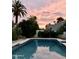 Backyard pool and palms with a vibrant pink sunset backdrop, creating a tranquil oasis at 3417 E Mission E Ln, Phoenix, AZ 85028