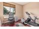 Well-lit office space with an exercise bike, desk, chair, and window offering views of the outdoors at 3680 S Tower Ave, Chandler, AZ 85286