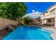 Sparkling blue pool in a private backyard with mature trees, patio, and a rock waterfall, offering a serene oasis at 3680 S Tower Ave, Chandler, AZ 85286