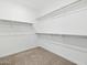 A walk-in closet features white walls and several rows of shelving for storage and clothes at 37357 W San Sisto Ave, Maricopa, AZ 85138