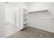 Walk-in closet with white shelving for clothing and storage plus view into bathroom at 37357 W San Sisto Ave, Maricopa, AZ 85138