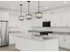 Modern kitchen featuring white cabinets, granite countertops, a stainless steel fridge, and stylish pendant lighting at 37357 W San Sisto Ave, Maricopa, AZ 85138