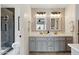 Stylish bathroom featuring dual sinks, a grey vanity, decorative mirrors, and a walk-in shower at 605 W Sandra Ter, Phoenix, AZ 85023