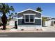 Manufactured home with blue and gray siding; accented by mature palm trees at 625 W Mckellips Rd # 111, Mesa, AZ 85201
