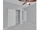 Bright bedroom features a ceiling fan, closet with white doors, and light gray walls and flooring at 6752 W Citrus Way, Glendale, AZ 85303