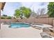 Backyard pool with stone accents, surrounded by brick fence and trees at 6833 W Tether Trl, Peoria, AZ 85383