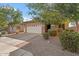 Charming single-story home featuring a well-maintained front yard, lush trees, and a two-car garage at 7818 S 74Th Ave, Laveen, AZ 85339