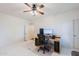 Bright bedroom featuring neutral carpet, ceiling fan, and desk setup, perfect for work or study at 9998 W Prospector Dr, Queen Creek, AZ 85144