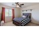 Cozy bedroom with a striped comforter, dark-stained wood, and a ceiling fan at 9998 W Prospector Dr, Queen Creek, AZ 85144