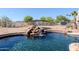 Backyard oasis with a pool and rock waterfall feature, surrounded by lush landscaping and fencing for privacy at 9998 W Prospector Dr, Queen Creek, AZ 85144