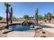 Backyard view of pool with rock waterfall feature, mature desert landscaping and shade umbrellas at 9998 W Prospector Dr, Queen Creek, AZ 85144