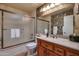 Traditional bathroom with single sink vanity, large mirror, frosted glass shower and warm lighting at 13731 W Greenview Dr, Sun City West, AZ 85375