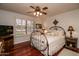 Cozy bedroom with a decorative metal bed frame, shuttered windows, and rich wood flooring at 13731 W Greenview Dr, Sun City West, AZ 85375