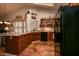 A kitchen featuring wood cabinets, black appliances, and terracotta tile flooring provides a functional and appealing space at 13731 W Greenview Dr, Sun City West, AZ 85375