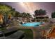 A magical backyard pool with rock waterfall and lush tropical landscape, great for relaxation under the stars at 14878 W Windrose Dr, Surprise, AZ 85379