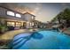 Backyard pool with a rock waterfall feature and lush landscaping, perfect for outdoor relaxation and entertainment at 14878 W Windrose Dr, Surprise, AZ 85379