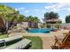Lounge by the backyard pool with a rock waterfall, palm trees, and ample seating areas, ideal for relaxation at 14878 W Windrose Dr, Surprise, AZ 85379