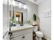 Cozy half bathroom features a white single sink vanity, white toilet, and decorative plants at 14878 W Windrose Dr, Surprise, AZ 85379