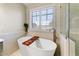 Bright bathroom featuring a soaking tub beneath a window with shutters, next to a glass shower at 14878 W Windrose Dr, Surprise, AZ 85379