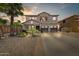 Charming two-story home showcasing a well-manicured desert landscape, palm trees and a three car garage at 14878 W Windrose Dr, Surprise, AZ 85379