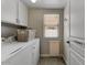 Functional laundry room includes ample cabinet space, modern washer and dryer, and a window for natural light at 14878 W Windrose Dr, Surprise, AZ 85379