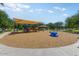 Playground featuring a shaded play structure with slides and swings, surrounded by a safe, wood chip ground at 14878 W Windrose Dr, Surprise, AZ 85379