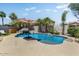 A backyard pool with a built-in rock waterfall, palm trees and lounge chairs at 14878 W Windrose Dr, Surprise, AZ 85379