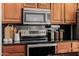 Close-up of the kitchen stove, microwave, and rich wood cabinets with modern stainless appliances at 1625 W Gunstock Loop, Chandler, AZ 85286